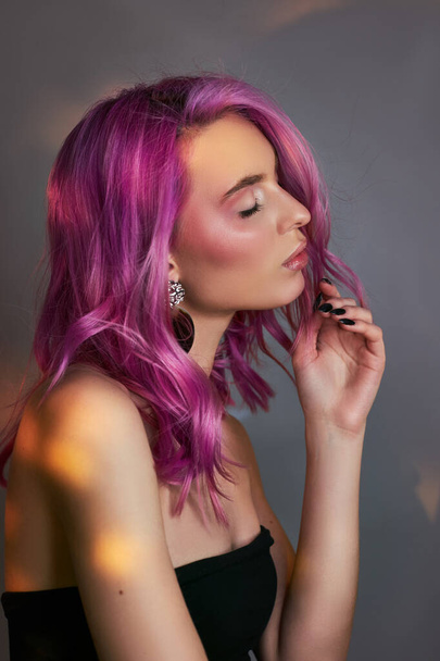 Portrait of a woman with bright colored flying hair, all shades of purple. Hair coloring, beautiful lips and makeup. Hair fluttering in the wind. Sexy woman with short  hair. Professional coloring - Foto, imagen