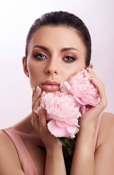 Beautiful brunette woman with peony flowers. Natural cosmetics and makeup, perfect skin - Фото, зображення
