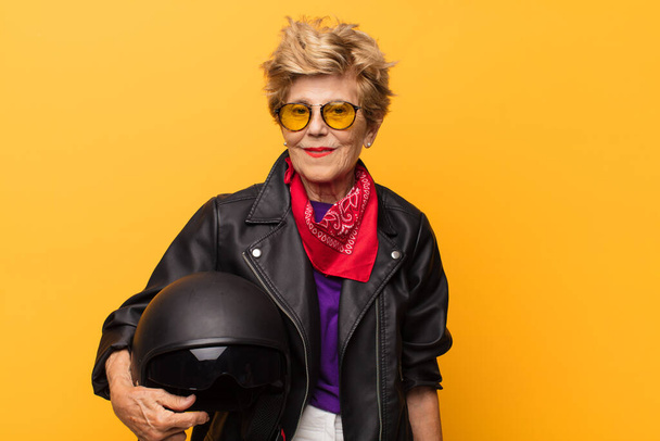 mature old beautiful woman looking happy and pleasantly surprised, excited with a fascinated and shocked expression. motorbike concept - Фото, зображення