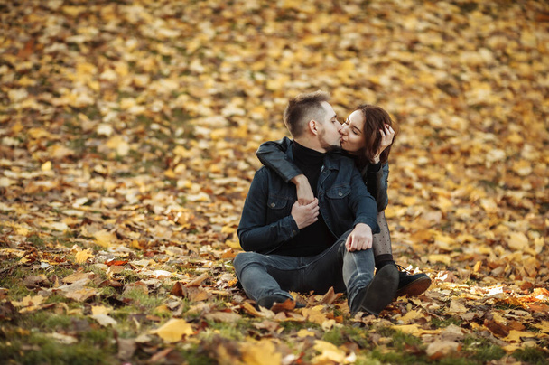 Ein junges Liebespaar umarmt sich auf einem verschwommenen Hintergrund herabgefallener Herbstblätter im Park. Romantisches, liebevolles Konzept - Foto, Bild