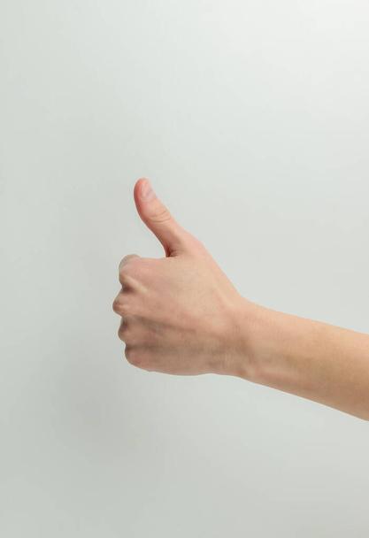 Mano femminile mostra pollice in su gesto su uno sfondo bianco - Foto, immagini