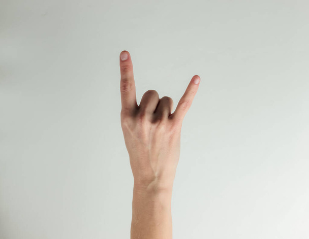 Женская рука показывает рок-жест на белом фоне - Фото, изображение