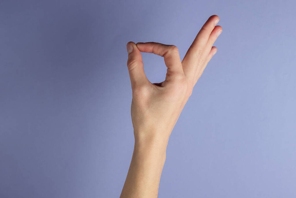 Female hand shows okay gesture on purple background - Photo, Image
