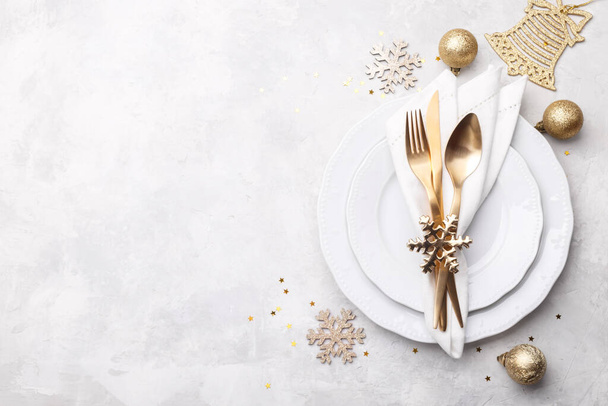 Χριστούγεννα ή το νέο έτος ρύθμιση τραπέζι με χρυσά μαχαιροπίρουνα σε λευκό πέτρινο τραπέζι, κάρτα ή μενού πρότυπο αντίγραφο χώρο επίπεδη lay - Φωτογραφία, εικόνα