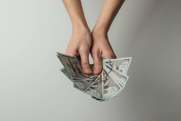 Les mains féminines tiennent un éventail de billets de cent dollars sur fond blanc. Concept de vie riche - Photo, image