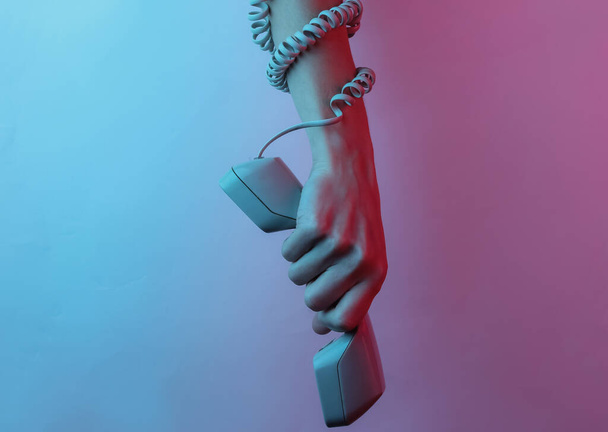 Femme enveloppé à la main dans le câble détient combiné rétro. Pop art créatif rose bleu néon couleur. Éclairage dégradé tendance. Lumière nocturne - Photo, image