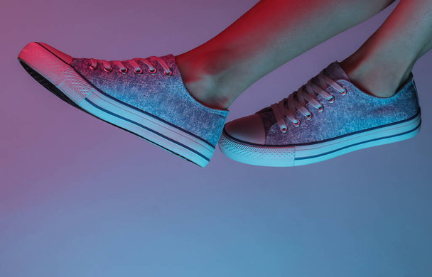 Női lábak tornacipővel. Creative pop art rózsaszín kék neon szín. Trendi gradiens megvilágítás. Éjszakai fény - Fotó, kép