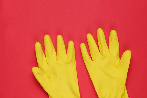 Kırmızı arka planı temizlemek için lateks eldivenler. Temizlik konsepti. Stüdyo çekimi. Üst görünüm - Fotoğraf, Görsel