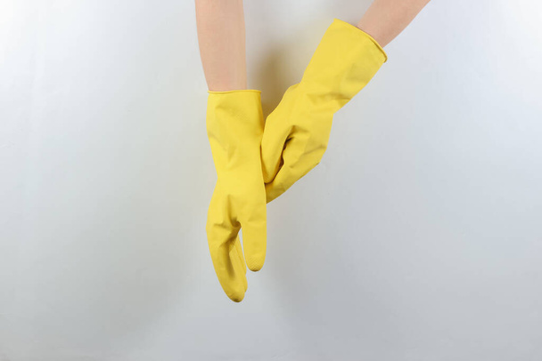 Концепция уборки дома. Женщины носят жёлтые резиновые перчатки для чистки на сером фоне - Фото, изображение