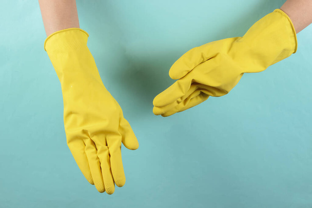 Mavi stüdyo arka planında sarı lastik eldivenli kadın eller. Ev temizliği konsepti. Ninja teması - Fotoğraf, Görsel