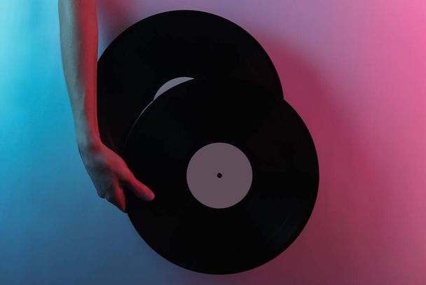 Onda retrô 80. Mão segurando discos de vinil. Criativa pop arte cor de néon azul rosa. Iluminação de gradiente na moda. Luz noturna - Foto, Imagem