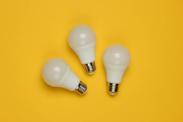 Three LED light bulbs on yellow background. Top view - Fotoğraf, Görsel