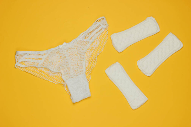 Women's panties and pads on a yellow background. Feminine hygiene concept. Critical days, menstruation. Top view. Flat lay - Photo, Image