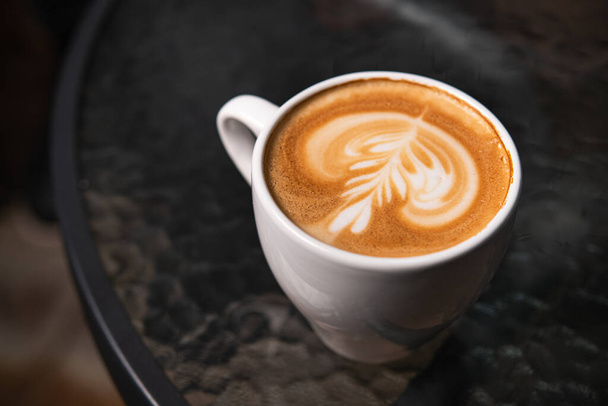 Cup of patterned coffee on foam on a cafe table - Fotografie, Obrázek