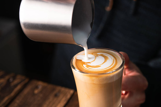 Barista nalewa świeże mleko i robi kawę cappuccino w kawiarni - Zdjęcie, obraz