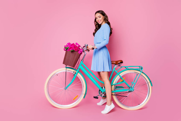 Full length body size profile side view of her she attractive cheerful wavy-haired lady florist riding bike wearing smart casual delivering fresh floristry order isolated pink pastel color background - Photo, image