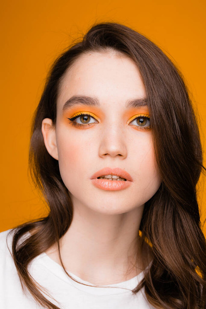 Девушка с ярким осенним макияжем на оранжевом фоне. Осенняя концепция, осенняя мода - Фото, изображение