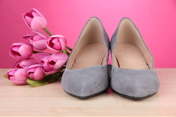 Beautiful grey female shoes and flowers on pink background - Foto, imagen
