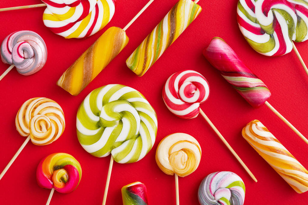 Lollypops leckere Süßigkeiten auf farbigem rotem Hintergrund. Trend Food Minimalkonzept. Flach gelegt. Ansicht von oben. - Foto, Bild