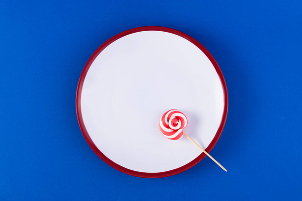 Falsche Ernährung. Leerer Teller mit Besteck in Form süßer Bonbons auf blauem Hintergrund. Konzept der ungesunden Ernährung. - Foto, Bild