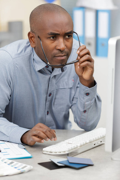 smiling businessman at office staring at computer screen - Photo, Image