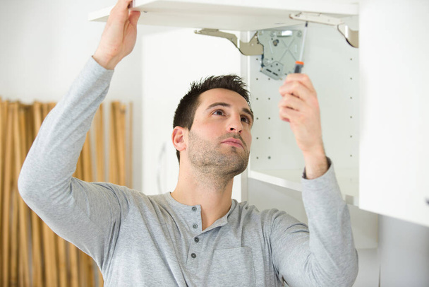 man tightening the cupboard hinges - Foto, imagen