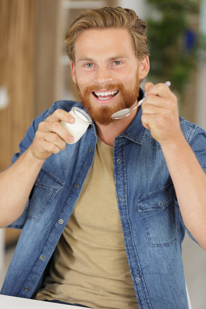 young happy man is eating yogurt - Zdjęcie, obraz