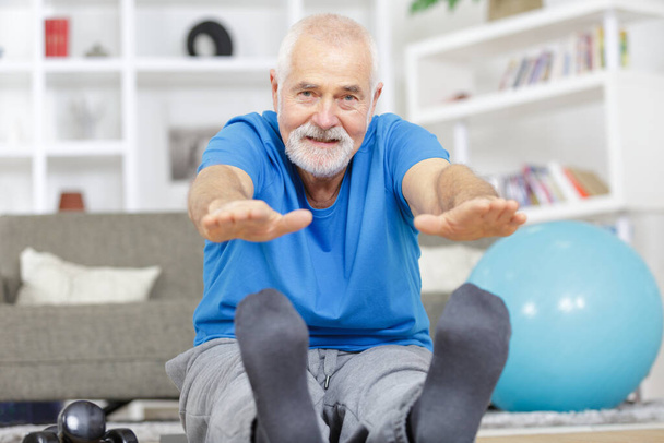 a mature man stretching legs indoors - Photo, image