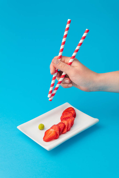 Creative image of fresh strawberries as sushi rolls on a blue background. - Фото, зображення
