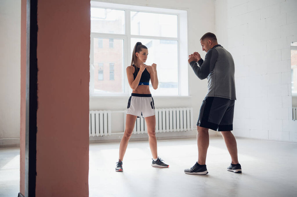 広々としたロフトでは、男性トレーナーと彼の女性のメンティーがボクシングトレーニングセッションを行います - 写真・画像