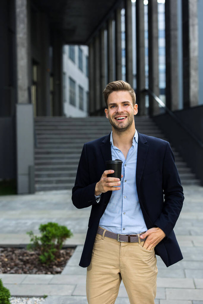 Portrait of handsome smiling man in casual wear. Successful young businessman.Young man standing on the city street near business center - Foto, Bild