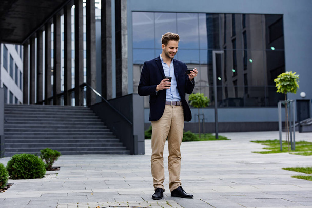 Handsome businessman using smartphone and smiling. Happy young man using mobile phone apps, texting message, browsing internet, looking at smartphone. Young people working with mobile devices - Fotoğraf, Görsel