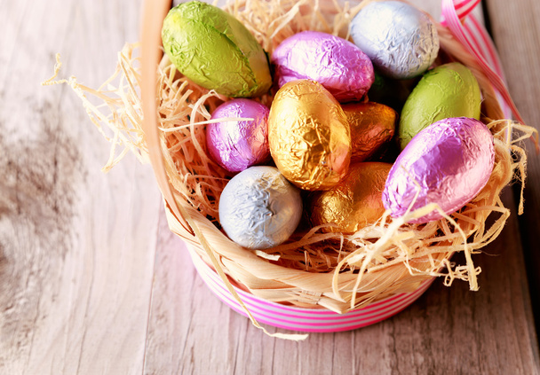 Coloridos huevos de Pascua en canasta de paja
 - Foto, Imagen