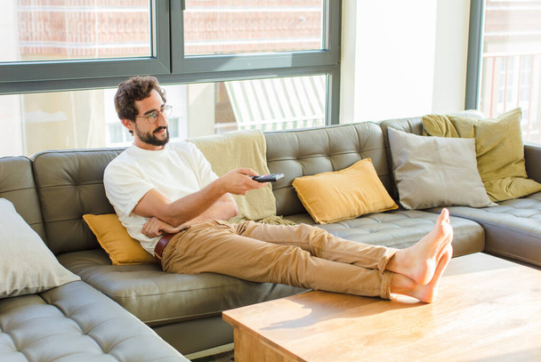 young bearded cool man sitting on a couch at home - Photo, image
