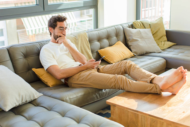 giovane uomo fresco barbuto seduto su un divano a casa - Foto, immagini
