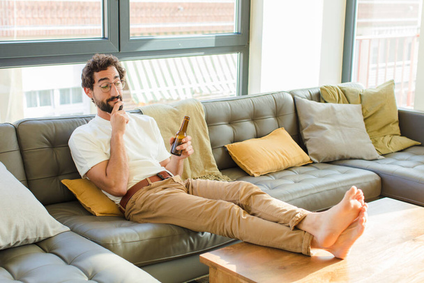 young bearded cool man sitting on a couch at home - 写真・画像