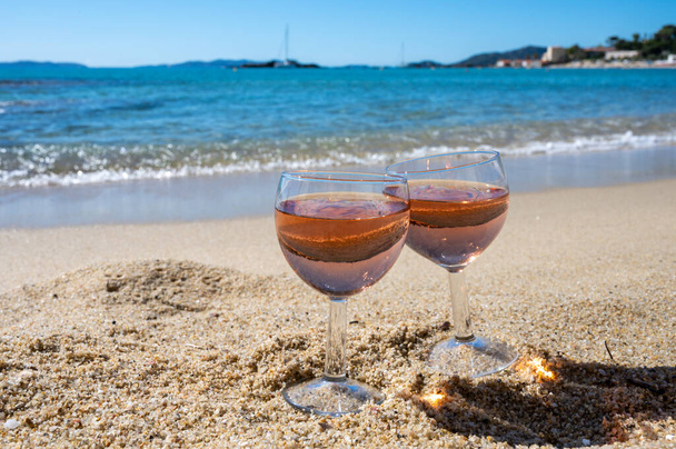 Dvě sklenice místního růžového vína na bílé písečné pláži a modré Středozemní moře na pozadí, v blízkosti Le Lavandou, Var, Provence, Francie - Fotografie, Obrázek