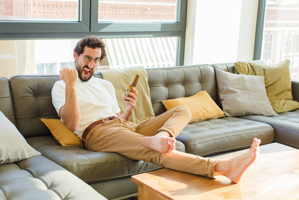 young bearded cool man sitting on a couch at home - Foto, Imagem