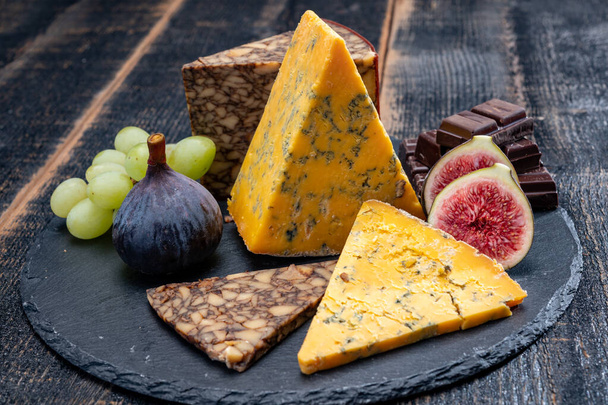 Britische und irische Käsesorten, Verkostungsteller mit Blue Shropshire, braunem Porter-Käse und geräuchertem Cheddar aus nächster Nähe - Foto, Bild