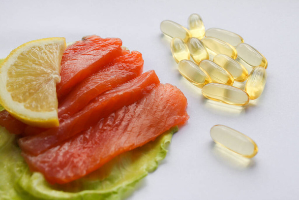 Омега-3 таблетки риб'ячого жиру у вигляді риб'ячого філе з лимоном і листям салату
. - Фото, зображення