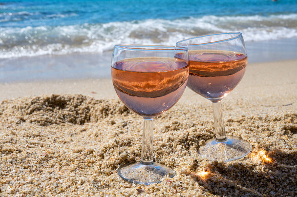 Due bicchieri di vino rosato locale sulla spiaggia di sabbia bianca e blu del Mediterraneo sullo sfondo, vicino a Le Lavandou, Var, Provenza, Francia - Foto, immagini