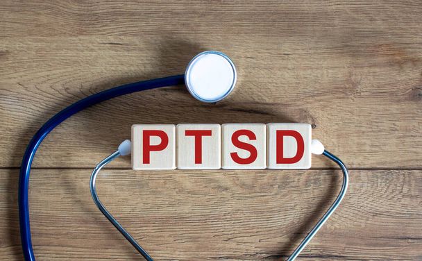 Concept word 'PTSD, post-traumatic stress disorder' on cubes on a beautiful wooden background. Stethoscope. Copy space, medical concept. - Foto, immagini