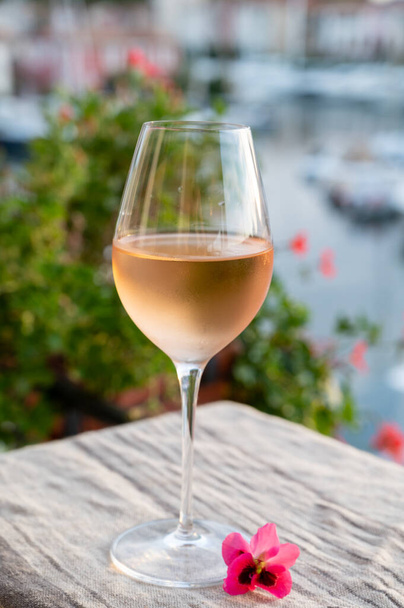 Ochutnávka místního studeného růžového vína v létě při západu slunce s plachetnicemi útočiště Port Grimaud na pozadí, Provence, Var, Francie - Fotografie, Obrázek