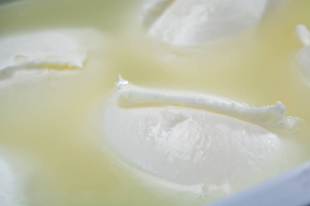 チーズショップ、カンパニア産の新鮮な手作りソフトイタリアチーズ、水を閉じ込めた容器で牛乳から作られた水牛のモッツァレラチーズの白いボール - 写真・画像