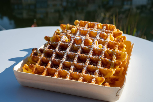 Sweet fresh baked Belgian waffles served outdoor with view on Maas river in Dinant, Wallonia, Belgium close up - Photo, Image