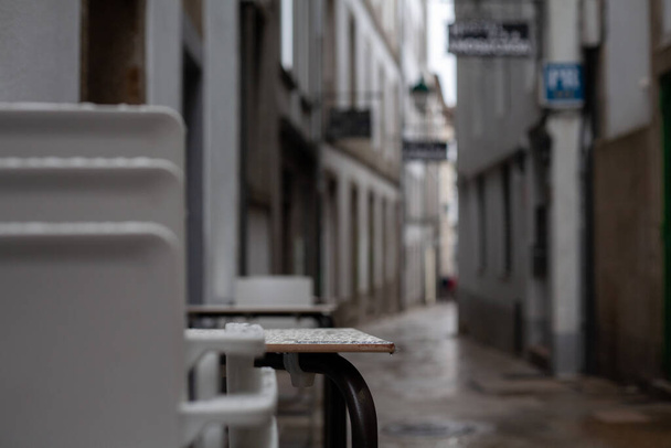 Stoh plastových židlí z restaurace outisde ve staré rustikální deštivé ulici Santiago de Compostela, Španělsko. Uzavřený skládaný cestovní ruch Španělsko rustikální. - Fotografie, Obrázek