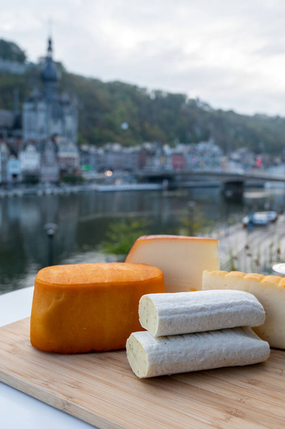 Colección de quesos, sabrosos quesos de la abadía belga hechos con cerveza trapense marrón y finas hierbas y vista del río Maas en Dinant, Valonia, Bélgica - Foto, Imagen