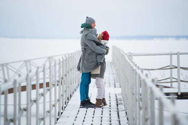 Μια συνάντηση ενός ερωτευμένου ζευγαριού το χειμώνα σε μια προβλήτα σε μια παγωμένη λίμνη - Φωτογραφία, εικόνα
