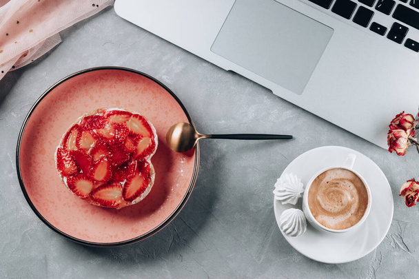 Cup of coffee, cake with strawberries and laptop. View from above. High quality photo - Fotó, kép