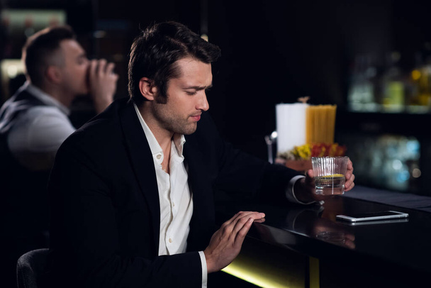 un giovane beveva molto al bar, seduto ubriaco al bar con un cocktail - Foto, immagini